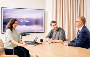 Tre Aixia-medarbetare runt ett konferensrum, vid en skärm det står Aixia på