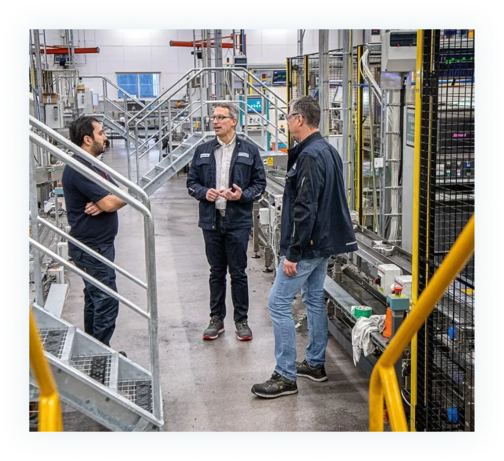 Tre personer står vid en dator hos Sansera